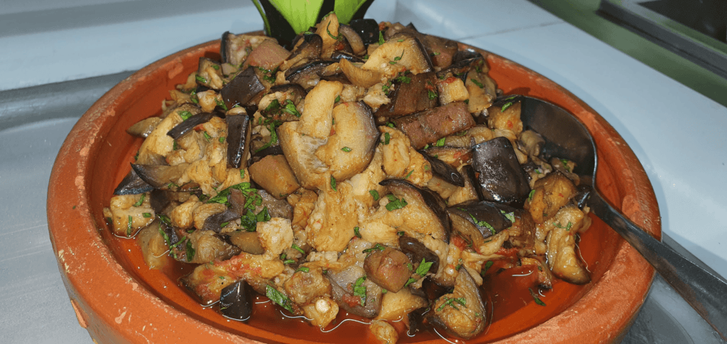 A bowl of Moroccan zaalouk, a smoky eggplant and tomato dip, garnished with fresh parsley and served with crusty bread